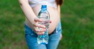 pregnant woman holding a plastic water bottle