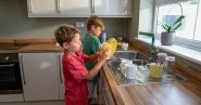 young boys doing dishes in a kitchen